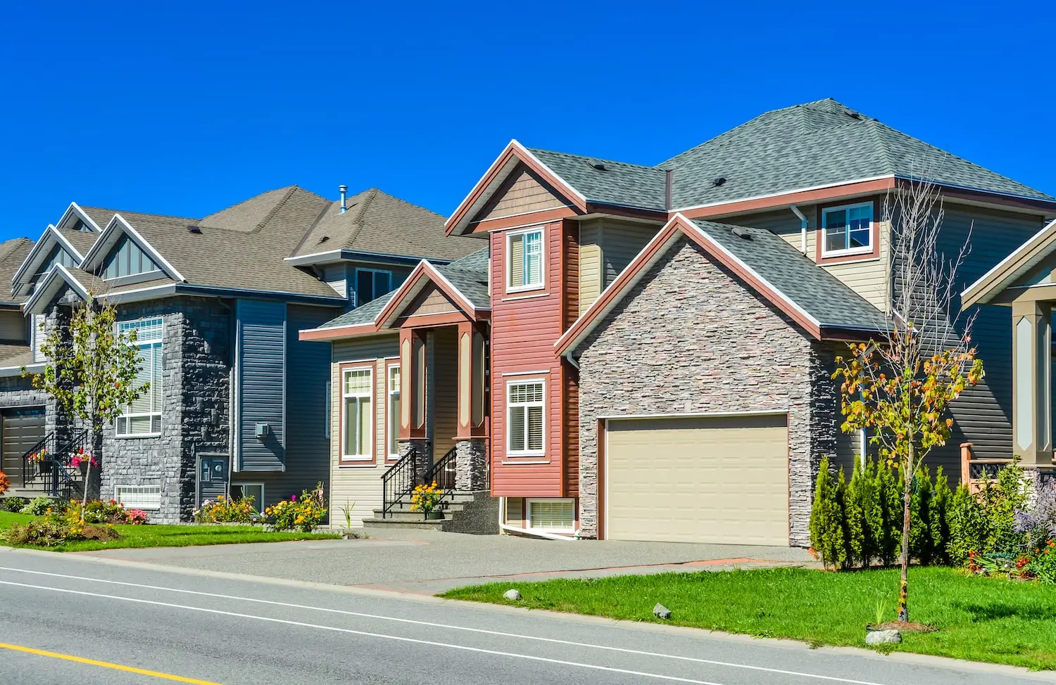 Two-story houses with front lawns along a suburban street